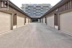 Row of garages featuring vertical wood siding and light-colored paneled garage doors - 