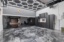 Garage interior featuring a distinctive epoxy floor, hexagonal ceiling lighting, and extensive built-in cabinetry - 