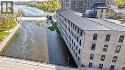 Stone facade building with multiple window openings bordering a waterway featuring a dam and river - 