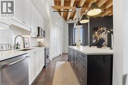 Kitchen featuring white shaker-style cabinetry, stainless steel appliances, and a subway tile backsplash - 