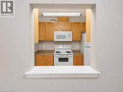 Pass-through window featuring a kitchen with wood-finish cabinetry, a white microwave, a white electric range, and a white refrigerator - 