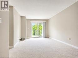 Spacious room featuring neutral wall tones, light-toned carpeting, a sliding glass door, and a private balcony with white railings - 