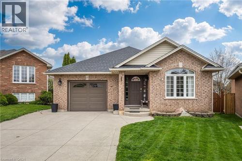 Brick facade home featuring a prominent arched window, a covered front entry, and an attached garage with a paved driveway - 47 Hannah Crescent, Hamilton, ON - Outdoor With Facade