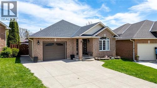 Brick exterior residence featuring a front-facing garage with an arched window, a prominent arched window on the facade, and a covered entry porch - 47 Hannah Crescent, Hamilton, ON - Outdoor With Facade