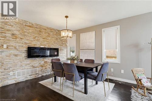 Accent wall featuring stacked stone veneer and a linear electric fireplace - 47 Hannah Crescent, Hamilton, ON - Indoor Photo Showing Dining Room With Fireplace