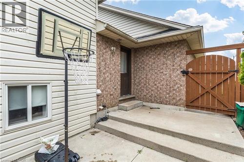 Concrete patio with multi-level steps, textured brick facade, wood privacy gate, and vinyl siding - 47 Hannah Crescent, Hamilton, ON - Outdoor With Exterior