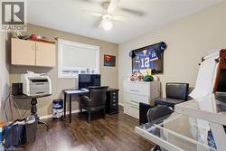 Room featuring wood-finish flooring, a ceiling fan with integrated lighting, and a window with a roller blind - 