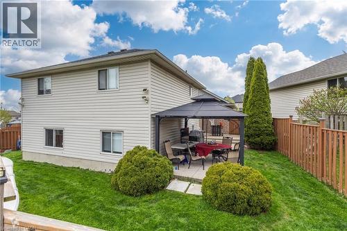 Rear exterior featuring beige siding, multiple windows, and a paved patio area - 47 Hannah Crescent, Hamilton, ON - Outdoor With Deck Patio Veranda