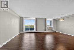 Spacious room featuring wood-finish flooring, light grey walls, and a contemporary rectangular chandelier - 