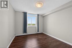 Room featuring a large window, dark wood-finish flooring, light grey walls, white trim, and a ceiling-mounted light fixture - 