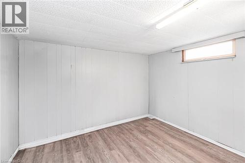 Room featuring wood-finish flooring, white paneled walls, a drop ceiling, and a high-set window - 112 Nash Road S, Hamilton, ON - Indoor Photo Showing Other Room