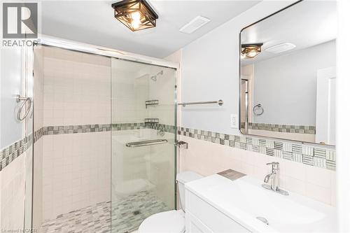 Bathroom featuring a glass-enclosed shower with mosaic tile flooring and a decorative tile accent band - 112 Nash Road S, Hamilton, ON - Indoor Photo Showing Bathroom