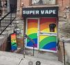 Storefront entrance featuring rainbow-colored window graphics and an ""Open"" sign - 449 Church Street, Toronto, ON 