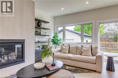 Living room featuring a fireplace with a textured surround, built-in shelving, recessed lighting, and large windows overlooking a wood deck - 1411 Mountain Grove Avenue, Burlington, ON - Indoor Photo Showing Living Room With Fireplace
