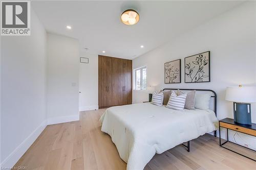 Bedroom featuring light wood-finish flooring, recessed lighting, a modern ceiling fixture, and a built-in wood-panel wardrobe - 1411 Mountain Grove Avenue, Burlington, ON - Indoor Photo Showing Bedroom