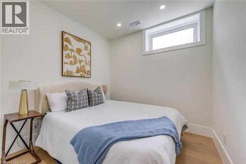 Light wood-finish flooring with white baseboards, recessed lighting, and a horizontal window with white trim - 1411 Mountain Grove Avenue, Burlington, ON - Indoor Photo Showing Bedroom