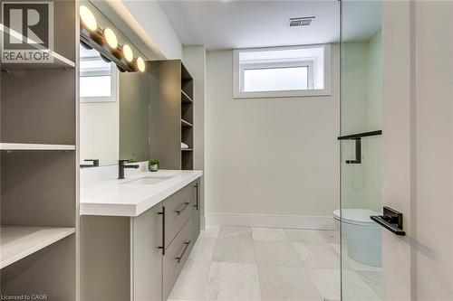 Contemporary vanity featuring a white countertop, matte black faucet, and ample storage cabinetry - 1411 Mountain Grove Avenue, Burlington, ON - Indoor Photo Showing Bathroom