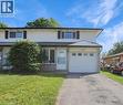 Two-story townhome featuring a neutral exterior siding, a white garage door with upper window panels, and a concrete driveway - 833 Doon Village Road, Kitchener, ON  - Outdoor With Facade 