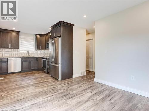 Kitchen featuring dark wood cabinetry, stainless steel appliances, and a patterned tile backsplash - 833 Doon Village Road, Kitchener, ON - Indoor Photo Showing Kitchen