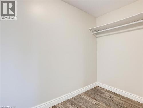 Interior closet space featuring white walls and wood-finish flooring - 833 Doon Village Road, Kitchener, ON - Indoor
