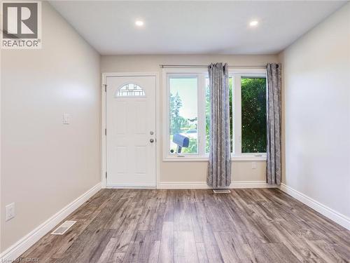 Entryway featuring wood-finish flooring, a white paneled door with arched transom, two large windows, white baseboards, and recessed lighting - 833 Doon Village Road, Kitchener, ON - Indoor Photo Showing Other Room