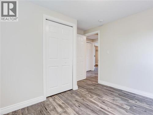 Room featuring wood-finish flooring, light-toned walls, white baseboards, and a white bi-fold closet door - 833 Doon Village Road, Kitchener, ON - Indoor Photo Showing Other Room
