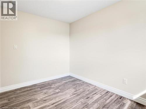 Interior room featuring light-toned walls, wood-finish flooring, and crisp white baseboards - 833 Doon Village Road, Kitchener, ON - Indoor Photo Showing Other Room