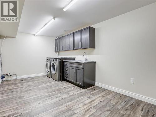 Laundry area featuring wood-finish flooring, white walls, and built-in cabinetry - 833 Doon Village Road, Kitchener, ON - Indoor Photo Showing Laundry Room