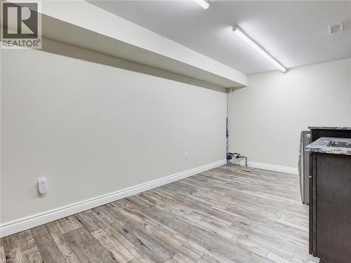 Spacious room featuring wood-finish flooring, white baseboards, and neutral wall tones - 833 Doon Village Road, Kitchener, ON - Indoor
