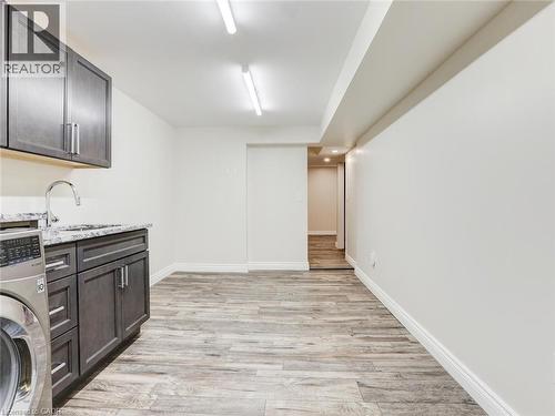 Utility room featuring wood-finish flooring, white baseboards, and bright overhead lighting - 833 Doon Village Road, Kitchener, ON - Indoor