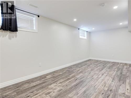 Spacious room featuring light gray wood-finish flooring, white walls, and recessed ceiling lighting - 833 Doon Village Road, Kitchener, ON - Indoor