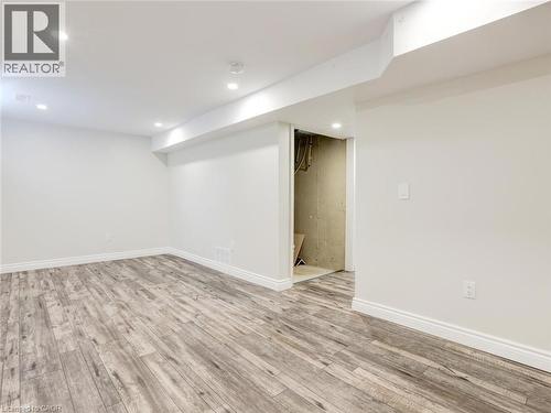 Spacious room featuring wood-finish flooring, white baseboards, recessed lighting, and crisp white walls - 833 Doon Village Road, Kitchener, ON - Indoor Photo Showing Other Room