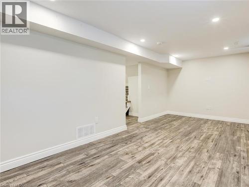 Finished lower level space featuring wood-finish flooring, recessed lighting, white baseboards, and neutral wall paint - 833 Doon Village Road, Kitchener, ON - Indoor
