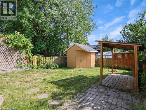 Expansive backyard featuring a covered patio with lattice detailing, a storage shed, a stone paver patio area, and mature perimeter trees - 833 Doon Village Road, Kitchener, ON - Outdoor