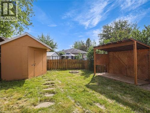 Expansive backyard featuring a shed, a covered patio area with lattice walls, a fire pit, and a wooden fence - 833 Doon Village Road, Kitchener, ON - Outdoor