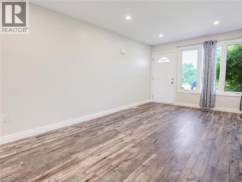 Spacious interior featuring wood-finish flooring, recessed lighting, and a white entry door with decorative glass - 833 Doon Village Road, Kitchener, ON - Indoor Photo Showing Other Room
