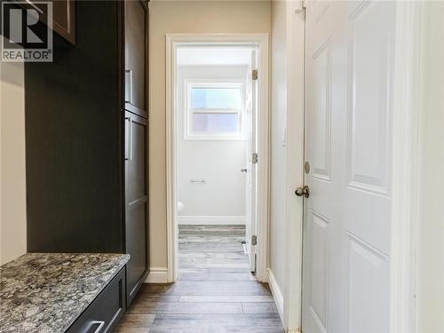 Hallway featuring wood-finish flooring, a white paneled door, and built-in cabinetry with a stone-finish countertop - 833 Doon Village Road, Kitchener, ON - Indoor Photo Showing Other Room