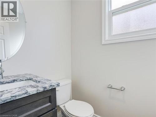 Bathroom featuring a dark wood-finish vanity with an integrated sink, patterned countertop, and a circular wall mirror - 833 Doon Village Road, Kitchener, ON - Indoor Photo Showing Bathroom