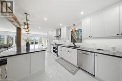 Kitchen featuring white cabinets, stainless steel appliances, pendant lighting, and plenty of natural light - 