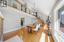 Dining area featuring light wood-style flooring, suspended lighting, and a high ceiling - 