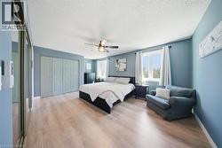 Bedroom featuring light wood finished floors, a closet, a ceiling fan, and a textured ceiling - 