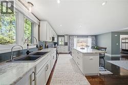 Kitchen with dark wood-style flooring, a kitchen bar, white cabinets, stainless steel range with electric stovetop, and a center island - 