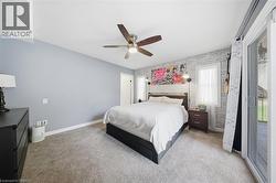 Carpeted bedroom with access to outside, brick wall, a ceiling fan, and an accent wall - 