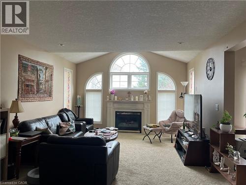 Living area featuring vaulted ceilings, a central fireplace with a mantel, and decorative arched windows - 350 Havendale Crescent, Waterloo, ON - Indoor Photo Showing Living Room With Fireplace