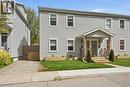 Multi-unit property featuring light gray horizontal siding, a covered front porch with natural wood accents, two separate entrances with paneled doors, and raised garden beds - 47 New Street, Hamilton, ON  - Outdoor With Facade 