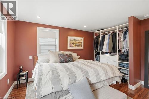 Bedroom featuring wood-finish flooring, two windows with white trim, recessed lighting, and an open closet system with integrated drawers and shelving - 47 New Street, Hamilton, ON - Indoor Photo Showing Bedroom