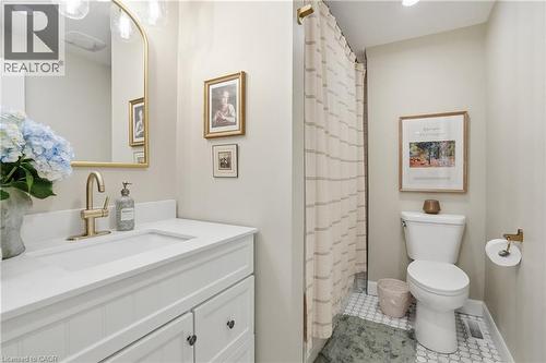 White vanity with shaker-style cabinetry, an integrated sink, and a gold-finish faucet - 47 New Street, Hamilton, ON - Indoor Photo Showing Bathroom