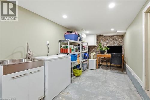 Lower level utility area featuring a stainless steel utility sink with a high-arch faucet, a stone accent wall, and recessed lighting - 47 New Street, Hamilton, ON - Indoor Photo Showing Laundry Room