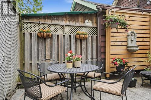 Patio area featuring stone pavers, a privacy fence with lattice detail, and a decorative wall fountain - 47 New Street, Hamilton, ON - Outdoor With Deck Patio Veranda With Exterior
