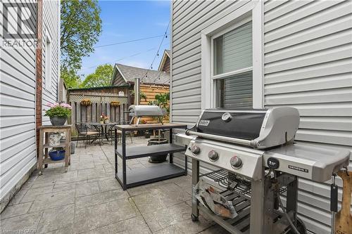 Paved side patio featuring a privacy fence, string lighting, and exterior siding - 47 New Street, Hamilton, ON - Outdoor With Deck Patio Veranda